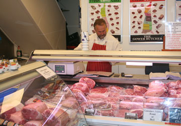 Inside Swansea shop picture, showing various meats and staff member